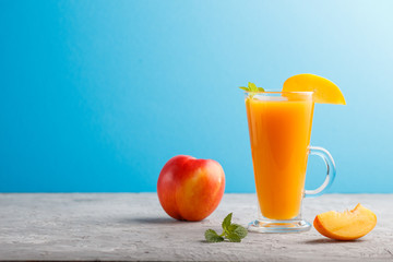 Glass of peach juice on a gray and blue background. Side view