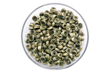 Twisted leaves of elite green tea on a round glass saucer. Green tea is the strongest antioxidant. View from above. Isolate on a white background. Soft focus.