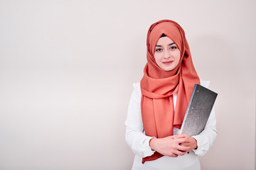 Young muslim girl look at the camera and holding file folder, back to school or education concept photo
