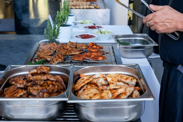 Meat sizzles on a large electric grill during a big barbecue party