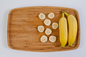 Banana em  prato de madeira no fundo branco