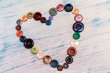Heart of colorful buttons on rustic background.