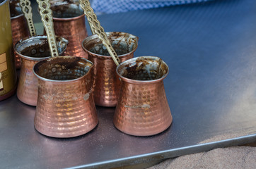 Coffee copper pots in sand. Traditional turkish coffee prepared on hot sand 