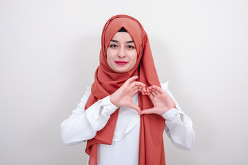 Young hijab muslim woman making a heart gesture with her fingers, muslim girl gesture love heart sign