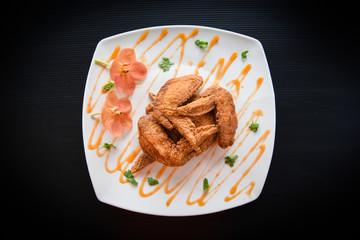 Fried chicken wings served on plate with sauce top view - plate of crispy chicken wings on black background , Thai Food Asian