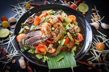Seafood salad spicy with fresh shrimp crab cockles served on black plate fresh vegetables herbs and spices ingredients with chilli tomato peanut garlic green papaya shredded