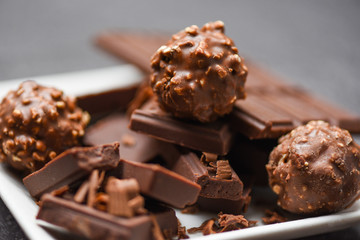 chocolate bar and chocolate ball on white plate on the dark background - chunks candy sweet dessert and snack