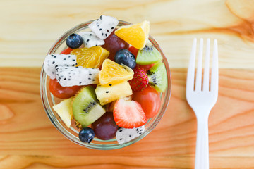Fruit salad bowl fresh summer fruits and vegetables healthy organic food strawberries orange kiwi blueberries dragon fruit tropical grape pineapple tomato lemon with fork