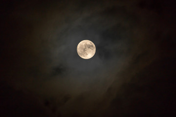 Full moon on the dark night shining on the sky in cloudy day.