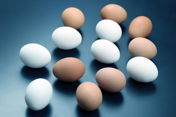 different chicken eggs lie on dark background.