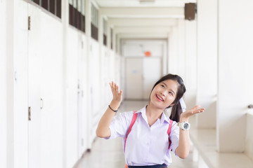 The schoolgirl in a white dress is looking at something on the head. Thai students are smiling in  the classroom.