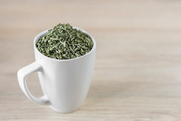 white cup with moringa leaves on wooden background