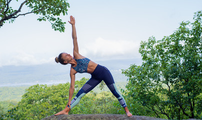 Young woman practicing yoga on stone outdoors harmony with nature.