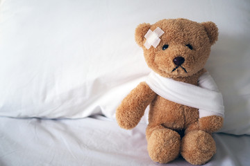 Teddy bear and bandage. Injury concept - obrazy, fototapety, plakaty