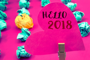 Words writing texts Hello 2018. Business concept for Starting a new year Motivational message 2017 is over nowClothespin hold holding pink heart with ideas words several crumpled papers