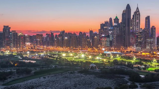 Dubai Marina skyscrapers and golf course day to night transition timelapse, Dubai, United Arab Emirates. Aerial view from Greens district after sunset