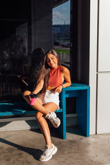 Naklejka premium Stylish happy young brunette woman wearing white shorts and sneakers holding pink cup of coffee to go.