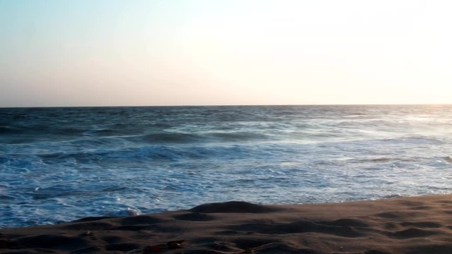 Camera moving along shoreline in Venice Beach at sunset