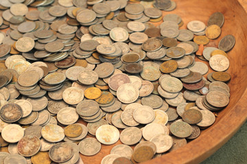 Many old coins in a wooden tray.