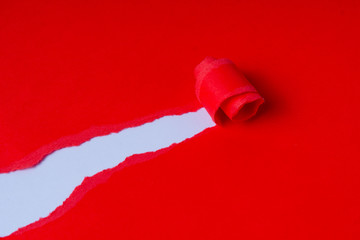 Torn red coloured paper on white background with closeup hole in the sheet of paper. Background concept with copy space.