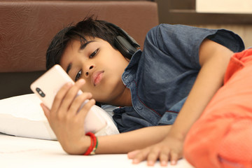 Cute boy listening to music on bed at bedroom for relax