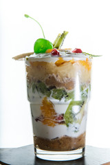 vertical view on layered cream and fruits dessert in glass