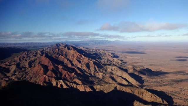 A great POV shot flying over the rugged Flinders Ranges from a chopper getting pushed from side to side by powerful winds, with the vast expanse of the Australian Outback distance.