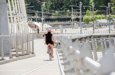 Woman Cyclist in a pink helmet rides a bicycle on the Tilikum Crossing Bridge