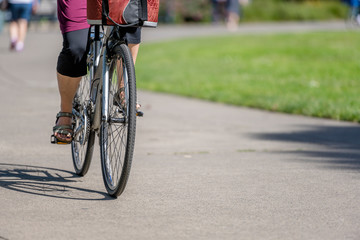 Woman with a bag rides a bicycle on a footpath