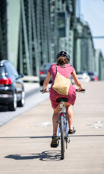 Woman with a bag rides a bicycle along a path on Hawthorne Bridge along a roadway