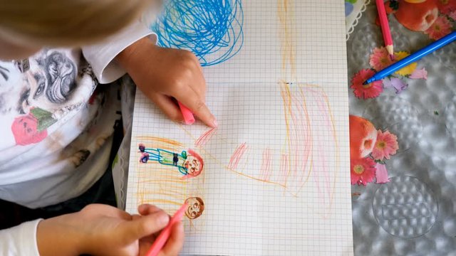 Happy child draws his family with a felt-tip pens on paper