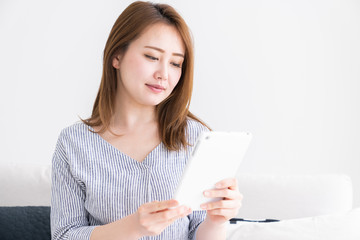 部屋でタブレットを見る女性