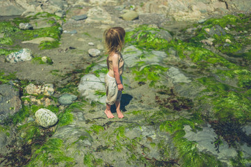 Little toddler standing on the beach in summer