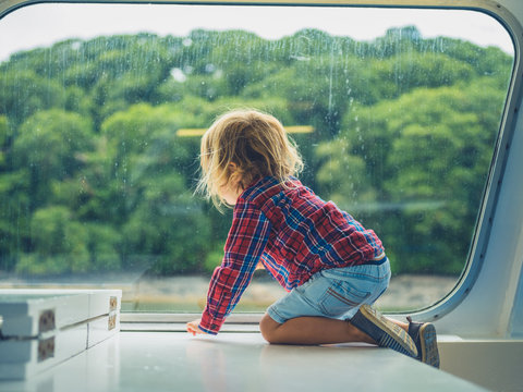 Little toddler by the window of a passenger ferry