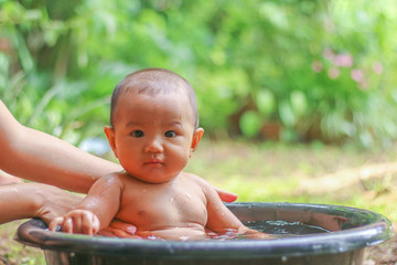 Asian baby in Bathtub  with her mother in the garden.