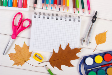 School accessories and orange leaves on white boards, back to school concept