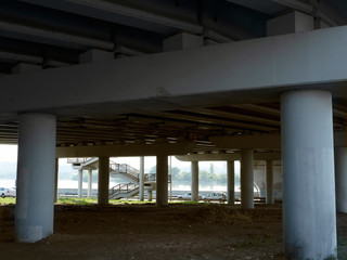 Road bridge over the river. Bottom view of concrete supports and metal structures.