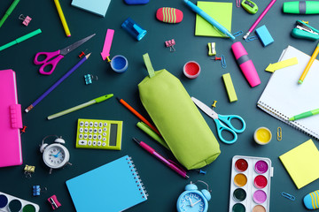Different bright school stationery on green background, flat lay