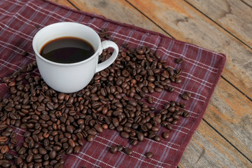 Coffee cup and coffee beans on dark red fabric, Coffee beans on wooden table