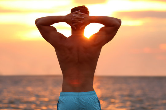 Handsome Young Man Posing On Beach Near Sea At Sunset