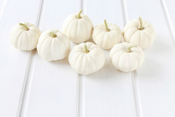 Baby boo pumpkins on white wooden table.