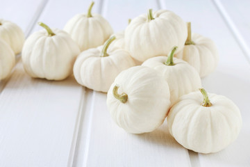Baby boo pumpkins on white wooden table.