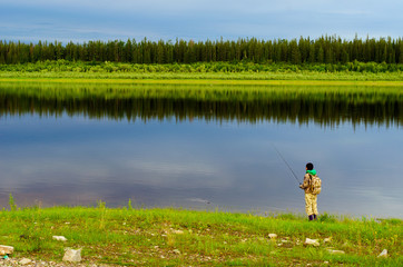 Yakut girl tourist angler with a backpack pulls out a spinning bait with the grass from North of...