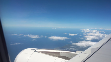 Fototapeta na wymiar Airplane turbine in the porthole window. Blue sky view from airplane window.