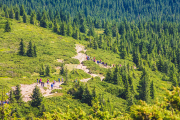 Tourists climb the mountain along a rocky trail_