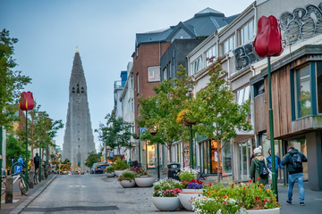 REYKJAVIK, ICELAND - AUGUST 11, 2019: City street with Cathedral on the background. The city hosts most of the island population - obrazy, fototapety, plakaty