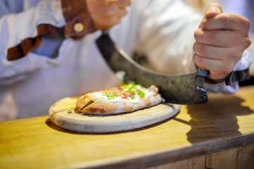 Traditional bread with sour cream and ham on German Christmas market. Closeup of fresh baked pretzel and hands of man on Xmas fair in Germany