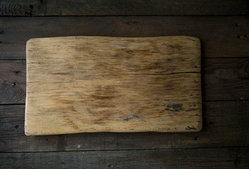 empty board on dark wooden background, top view.