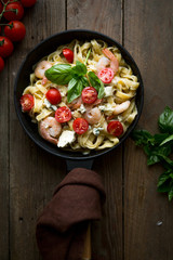 Tagliatelle pasta with shrimps and tomato sauce on dark background. Italian cuisine. Top view