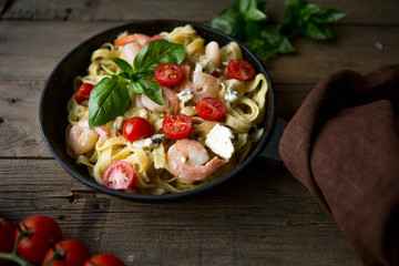 Tagliatelle pasta with shrimps and tomato sauce on dark background. Italian cuisine. Top view